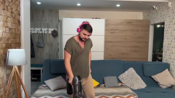 Junger Mann Hat Spaß Staubsauger Hause Musik Mit Rosa Kopfhörern — Stockvideo