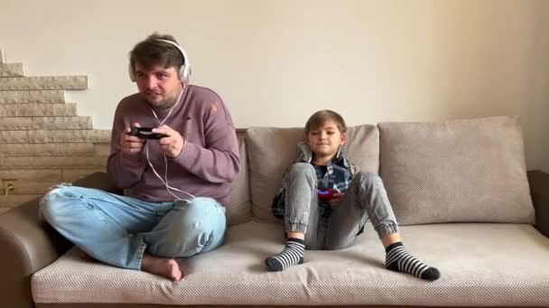 Πατέρας Και Γιος Κάθονται Στον Καναπέ Στο Σαλόνι Παίζοντας Βιντεοπαιχνίδι — Αρχείο Βίντεο
