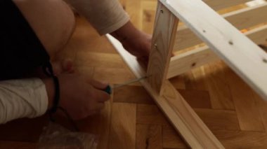 Yeni ahşap bir raf ve mobilya monte eden bir adam.