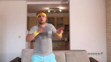 Modern hareketlerle dans eden pozitif komik sporcu evde antrenmandan önce ısınıyor. Şık eşofmanlı seksi bir adam spor salonuna hazırlanıyor.. 