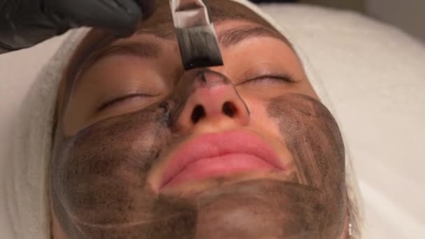 Cosmetólogo Aplicando Máscara Negra Cara Mujer Bonita Usando Guantes Negros — Vídeo de stock
