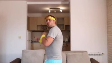 Modern hareketlerle dans eden pozitif komik sporcu evde antrenmandan önce ısınıyor. Şık eşofmanlı seksi bir adam spor salonuna hazırlanıyor.. 