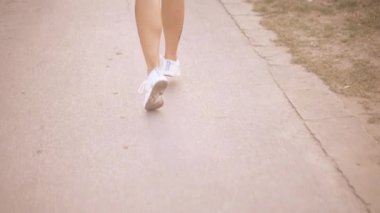 Spor ayakkabılı kadınların bacakları parkta yol boyunca koşar. Kilo kaybı ve zindelik. 