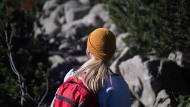 Açık arazide yürüyen heyecanlı bir kadın. Aktif bir kız orman dağlarında tatilinin tadını çıkarıyor. Yürüyüşe çıkmış gülümseyen bir turist. Neşeli bir kaşif turist macerasına çıkıyor.