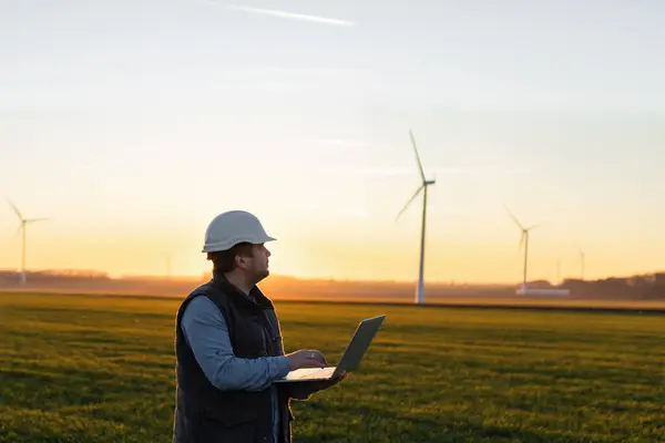 stock image Electrical engineers working at wind turbine power generator station with laptop computer.