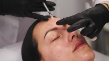 Güzellik kliniği. Eldiven giymiş güzellik uzmanları kadın derisine yüz yaşlanma enjeksiyonu yapıyor. Bir kadın güzellik yüz kozmetolojisi prosedürünü uygular. Botoks. Kolajen enjeksiyonları. 