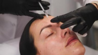 Güzellik kliniği. Eldiven giymiş güzellik uzmanları kadın derisine yüz yaşlanma enjeksiyonu yapıyor. Bir kadın güzellik yüz kozmetolojisi prosedürünü uygular. Botoks. Kolajen enjeksiyonları. 