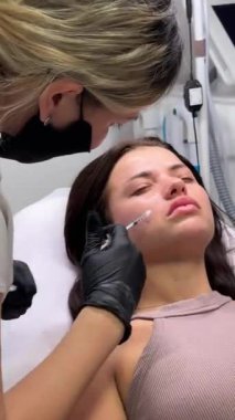 Dudak büyütme için enjeksiyon prosedürü, yakın plan. Kozmetik uzmanı müşterinin dudaklarına yavaşça ve dikkatlice dolgu yapar. Yüz bakımı, gençlik ve güzellik için reklam kavramı. 