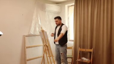 Erkek sanatçı resim yapar ve stüdyoda dans eder.. 