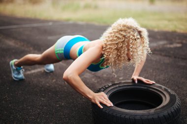 Genç, kıvırcık, atletik yapılı bir sarışın stadyumda antrenmandan önce ısınma turu yapıyor. Açık hava sporları. 