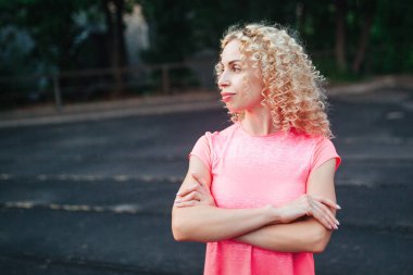 Genç, kıvırcık, atletik yapılı bir sarışın stadyumda antrenmandan önce ısınma turu yapıyor. Açık hava sporları. 