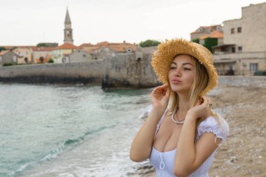 Hasır şapkalı beyaz kadın, Karadağ 'ın Budva kentindeki gözlem güvertesinde dikiliyor.