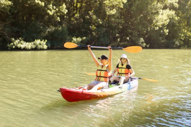 Nehirde yüzen ve gülümseyen iki genç kadın