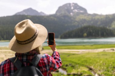 Seyahat ederken selfie. Genç bir kadınla manzara, yeşil tepeler ve göl. Yaşam tarzı, macera, doğa, aktif yaşam
