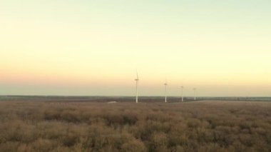 Yükseklerdeki bulutlu gökyüzünde enerji üretimi için güçlü rüzgar türbini çiftliğinin hava manzarası. Rüzgar güç türbinleri sürdürülebilir kalkınma için temiz yenilenebilir enerji üretiyor.