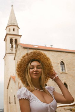 Hasır şapkalı beyaz kadın, Karadağ 'ın Budva kentindeki gözlem güvertesinde dikiliyor.