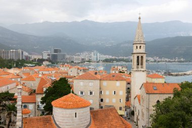 Kırmızı çatıları ve kilise çan kuleleri olan eski ortaçağ taştan evleri. Budva, Karadağ 'ın turizm merkezi ve bir yaz tatili beldesi. Karadağ 'da hava aracı şehir manzarası