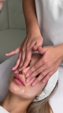 Kapalı gözlerle uzanmış spa salonunda yüz masajı yaptıran oldukça rahat genç bir kadının portresi. Bayan müşteri cilt bakımı tedavisinden zevk alıyor. Sağlık ve güzellik günü konsepti. Yüksek