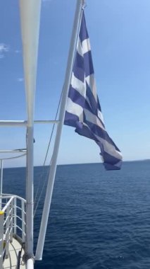 Yunan ulusal bayrağı dalgalanıyor ve su bir sürat teknesi tarafından uyandırılıyor. Yüksek kalite 4k görüntü