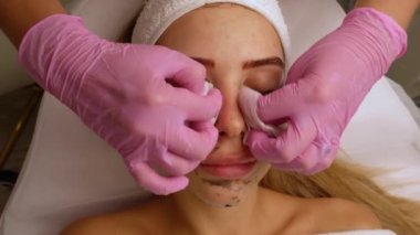 Güzellik uzmanları kozmetoloji ameliyatından sonra kadının yüzünü peçeteyle siliyorlar. Kozmetik prosedürü. Spa tedavisi konsepti. Yüz bakımı, kozmetoloji