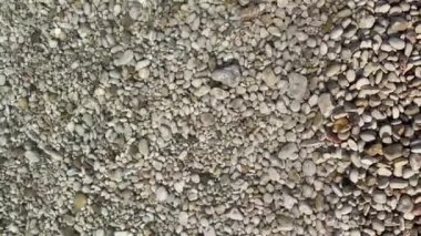 Çakıl taşlı bir plajda yavaşça akan deniz suyunun rahatlatıcı görüntüsü. Adriyatik plajından sakin ve meditasyon dolu bir yaz sahnesi. Kristal berrak deniz beyaz kayaların üzerinden akıyor.