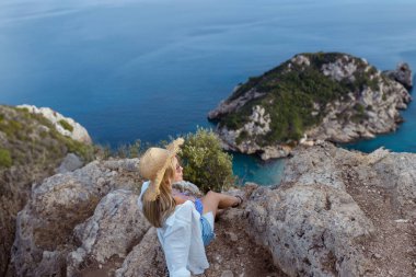Şapkalı bir kız oturur ve Porto Timoni Plajı, Afionas 'ın güzel manzarasına bakar. Yunanistan 'daki Korfu Adası. Yüksek kalite fotoğraf