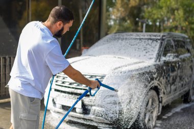 Otomobil yıkama istasyonunda köpüklü araba yıkayan bir adam. Araba self-servis istasyonunu yıka. Yüksek kalite fotoğraf