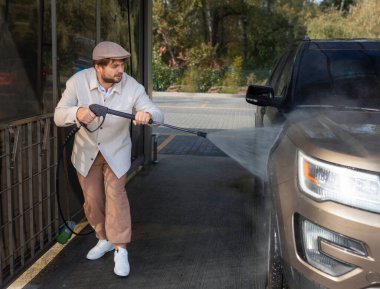 Otomobil yıkama istasyonunda köpüklü araba yıkayan bir adam. Araba self-servis istasyonunu yıka.