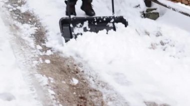 Karları kaldırmaya yakın çekim. Büyük kafesli bir adam dışarıda kar temizliyor..