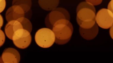 Sıcak turuncu Bokeh ışıkları siyah arkaplanda hareket ediyor, soyut ışık desenleri.