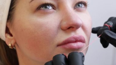 Kozmetik uzmanlarının salonunda dudaklarında kalıcı makyajı olan genç bir kadın. Kalıcı makyaj dövmesi. Kırmızı dudaklı bir çizgi çiz. 