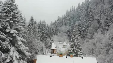 Hava manzaralı. Dağlarda ahşap bir ev. Kışın bacadan duman çıkıyor..