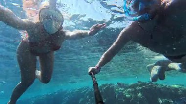 Kızıl Deniz 'de şnorkelle yüzen genç bir çift güzel selfie çekiyor. İnsanlar çarpıcı tropikal sulara dalıp selfie çekiyorlar. . 