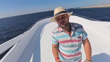 Şapkalı mutlu adam denizdeki teknesiyle Kızıl Deniz 'de yat gezintisi yapıyor.. 