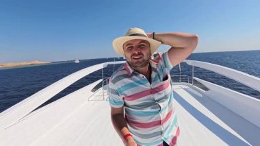 Şapkalı mutlu adam denizdeki teknesiyle Kızıl Deniz 'de yat gezintisi yapıyor.. 