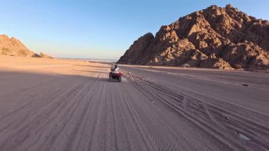 Mısır 'ın Sharm el Sheikh yakınlarındaki çölde bisiklet sürmek. ATVSand ve Sand Borkhan' daki çöl off-road maceraları. Kaya ve gün batımı. Dörtlü Bisiklet Seyahati. İnsanlarla Gezinti. 