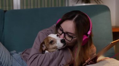 Çekici kız müzik dinliyor ve evde bir köpek gibi tablette video klipler izliyor..