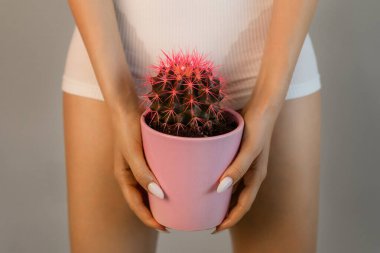  Saç çıkarma, pürüzsüzlük kavramı. Elinde iç çamaşırlı turuncu bir kaktüs olan bir kadın. 