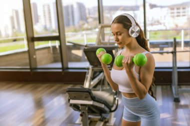Spor salonunda dumbbells ile çalışma dışarı çekici genç kadın