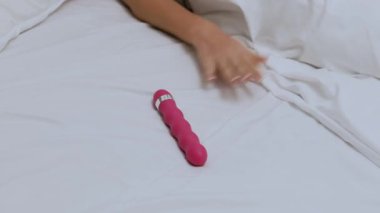 Young woman holding dildo on bed. Girl chooses a vibrator. lot of sex toys.