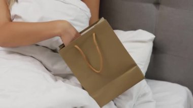 Young woman holding dildo on bed. Girl chooses a vibrator. lot of sex toys.