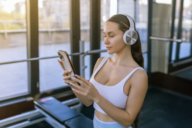 Spor salonunda müzik dinleyen akıllı telefonlu genç bir kadının portresi. Yüksek kalite fotoğraf