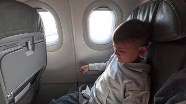 Yüzünü kapatıp ağlayan bir çocuğun yakın plan görüntüsü. Uçakta baş ağrısı, uçakta korkmuş ve kötü hisseden bir çocuk. Yüksek kalite 4k görüntü