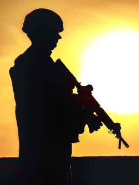 Gün batımında tüfekli Amerikan askerinin silueti arka planda güneş batarken duruyor, ulusal gurur.