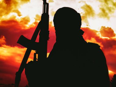 Çölde gün batımında tüfekli Müslüman militanlar