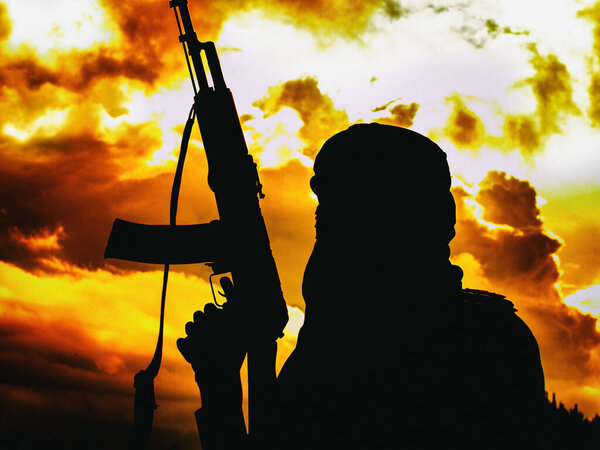 Мусульманский боевик с винтовкой в пустыне на закате с автоматом АК