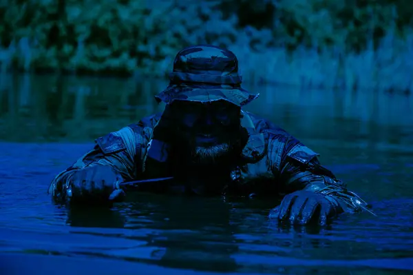 Ein Getarnter Soldat Dringt Durch Sumpfige Gewässer Vor Ein Messer lizenzfreie Stockfotos