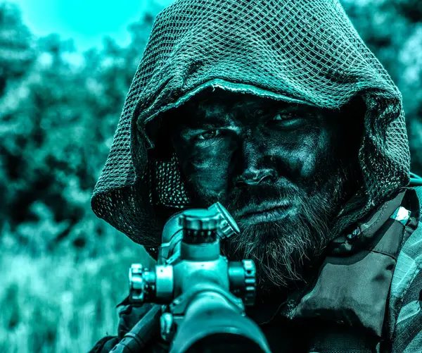 一个伪装的士兵 带着锐利的目光 穿着战术性装备 在丛林的沼泽地里守望着 用来复枪把肖像合上 图库图片