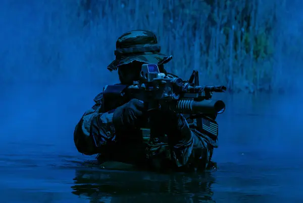 一名留胡子的士兵在水里执行监视任务 在沼泽地中行走 四周雾蒙蒙的 枪林弹雨 随时准备应对迫在眉睫的威胁 枪弹呈彩色 图库图片