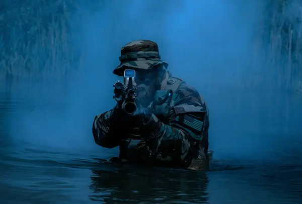 一名留胡子的士兵在水里执行监视任务 在沼泽地中行走 四周是夜雾 随时准备着来复枪以应对迫在眉睫的威胁 枪弹呈彩色 免版税图库照片